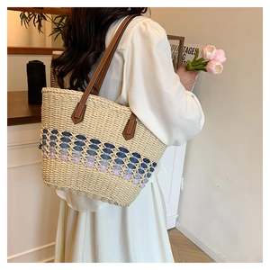 Détail d'un sac cabas en paille tissée avec motif dégradé bleu et bandoulière en cuir