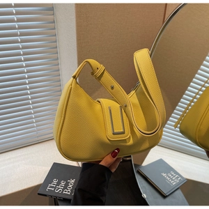 Detail of a yellow dumpling bag with lychee grain texture and a rectangular metal buckle