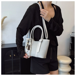 Porté d'un sac cabas tressé blanc avec chaîne contrastée et design minimaliste chic