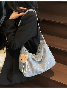Hobo-Tasche mit Blumenmuster und Bärenanhänger getragen von einem Model im Studio
