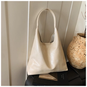 Close-up of minimalist beige hobo bag with wide handle on a minimalist dark pedestal