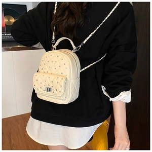 Detail of quilted beige backpack with rhinestone accents and woven chain straps