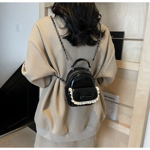 Mini black backpack with white lace trim and bow on model in casual knit sweater