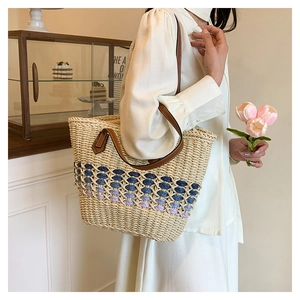 Détail d'un sac cabas en paille tissé à la main avec motif dégradé bleu et anses en cuir