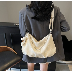 Detail of a large cream-white hobo bag featuring silver chain and plush bear charm
