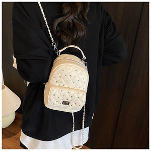 Detail of cream quilted mini backpack with rhinestones and metal chain strap shown on back