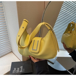 Macro detail of yellow pebbled leather crescent bag with silver metallic U-shaped buckle