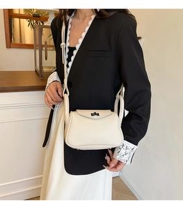 Detail of cream leather shoulder bag with silver turn-lock and lychee grain texture