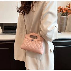 Detailed view of pink quilted handbag with chain strap and silver twist lock on model