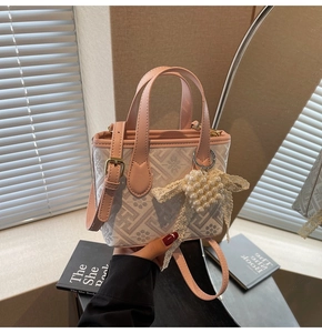 Detail showing pink canvas handbag with floral patterns, leather handles and pearl heart charm