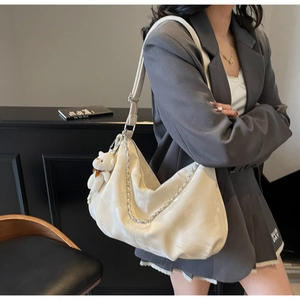 Close-up of white PU leather tote bag featuring a silver chain and plush bear charm