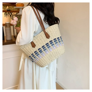 Grand sac cabas en paille tissée avec accents bleus sur un modèle dans un café chic