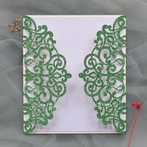 Detail of emerald laser-cut invitation cover with glitter finish and scrollwork patterns
