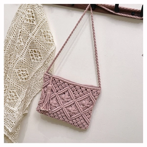 Détail du sac bandoulière en macramé rose avec texture losange et pompons frangés
