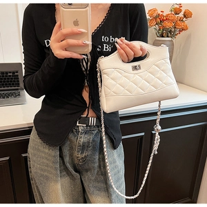 Close-up of white quilted handbag with silver chain strap and metal turn-lock closure