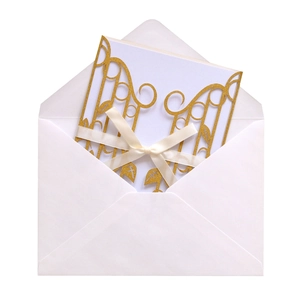 Elegant gold laser-cut wedding invitation set with white ribbon bow and envelopes