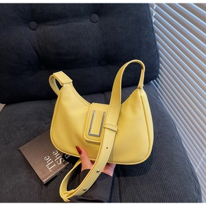 Detailed macro view of yellow lychee-textured leather bag with silver buckle finish