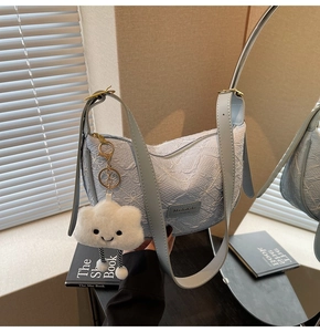 Detailed view of light blue dumpling bag with floral texture and plush cloud charm