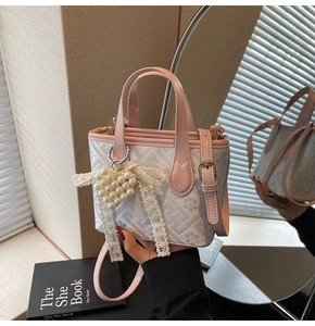 Close-up of geometric pattern crossbody bag with pearl heart charm and lace bow detail