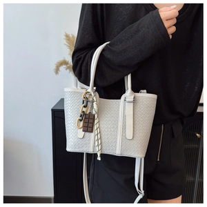 Détail du sac à main gris clair à texture tissée avec bandoulière et pendentifs