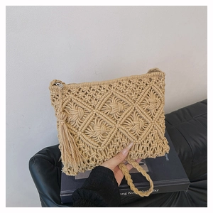 Detail of beige woven clutch bag featuring diamond patterns and side tassel accents