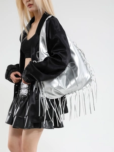 Silver metallic tote bag with long tassels and drawstring details on a female model