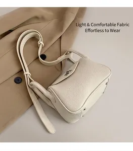 Close-up of off-white lychee grain leather bag with silver metal twist lock and studs