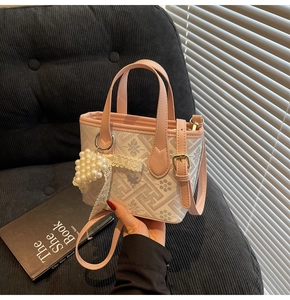 Close-up of pink leather tote bag featuring floral prints and a pearl heart pendant accessory
