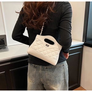 Detail view of a white quilted chain bag featuring a silver twist lock and metal strap