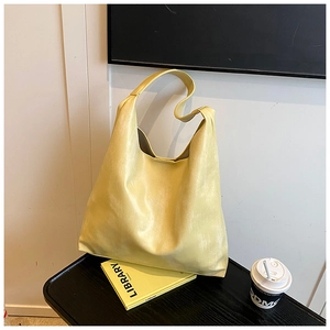 Detail of soft pale yellow hobo bag with seamless strap on a minimalist black display