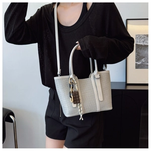 Détail d'un sac à main tressé gris avec breloque chocolat et chaîne décorative chic