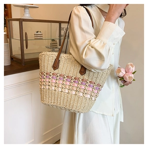 Détails des motifs tissés colorés et des anses en cuir marron du sac de plage