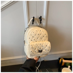 Detail of cream quilted backpack with sparkling rhinestones and silver chain straps