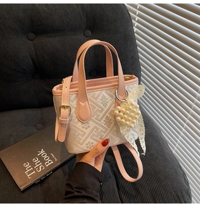 Detail of pink leather handle and floral pattern bag with heart pearl lace charm