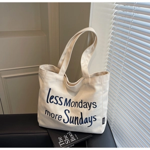 Detail of embroidered 'less Mondays more Sundays' slogan on cream canvas tote bag