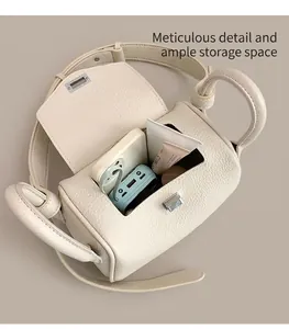 Detail view of the spacious interior of an off-white pebble leather barrel crossbody bag