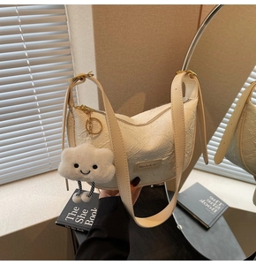 Detail of cream white dumpling bag with textured fabric and plush cloud charm