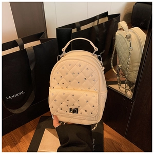 Detail of quilted beige mini backpack with rhinestone decor and chain strap