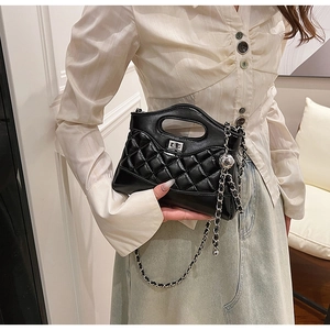 Detail of black quilted leather handbag with silver twist lock and chain strap