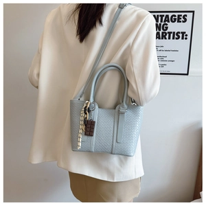 Vue détaillée du sac à main bleu clair tissé avec breloque chocolat et chaîne décorative