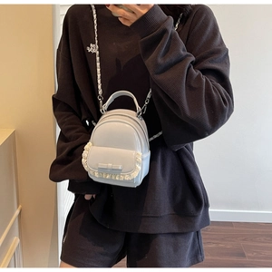 Close-up of light blue lacquer backpack with white lace trim and bow on a casual model