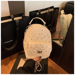 Detail of cream quilted mini backpack with sparkling rhinestones and silver chain straps