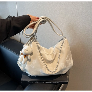 Detail of off-white hobo bag featuring marble texture, chain strap, and cute teddy charm