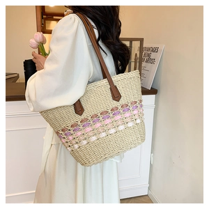 Détail du sac cabas en paille tressée avec motif dégradé rose et bandoulière en cuir