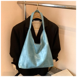 Detail view of the light blue suede hobo tote bag hanging on a minimalist display