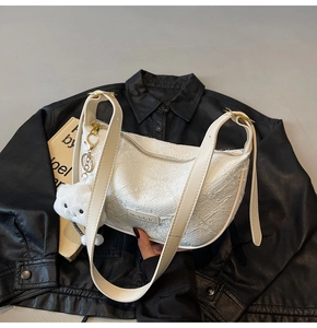 Close-up of white pleated dumpling bag with gold hardware and plush cloud charm