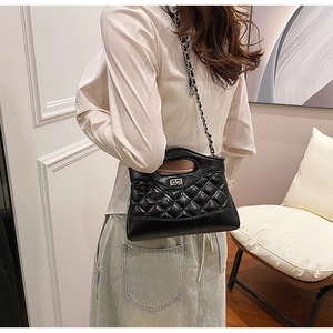 Detail of black quilted leather handbag with metal turn-lock and chain strap