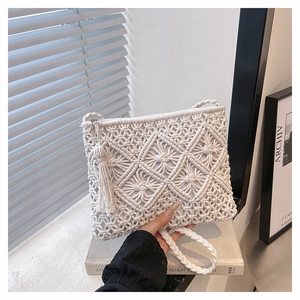 Détail du motif en diamant tissé sur pochette en coton crème avec pompon latéral