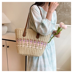 Détail du sac cabas en paille tissée avec rayures colorées et anses en cuir marron