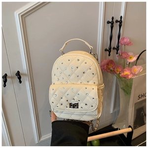 Detail of cream quilted mini backpack with rhinestone embellishments and metal twist lock